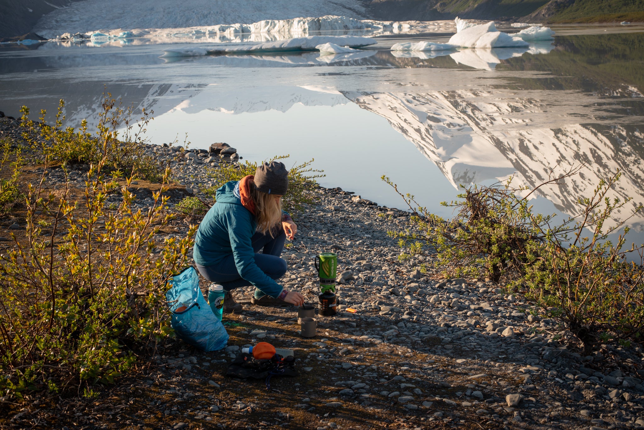 Cooking on a stove camping in Alaska wearing Alpine Fit hat and base layers
