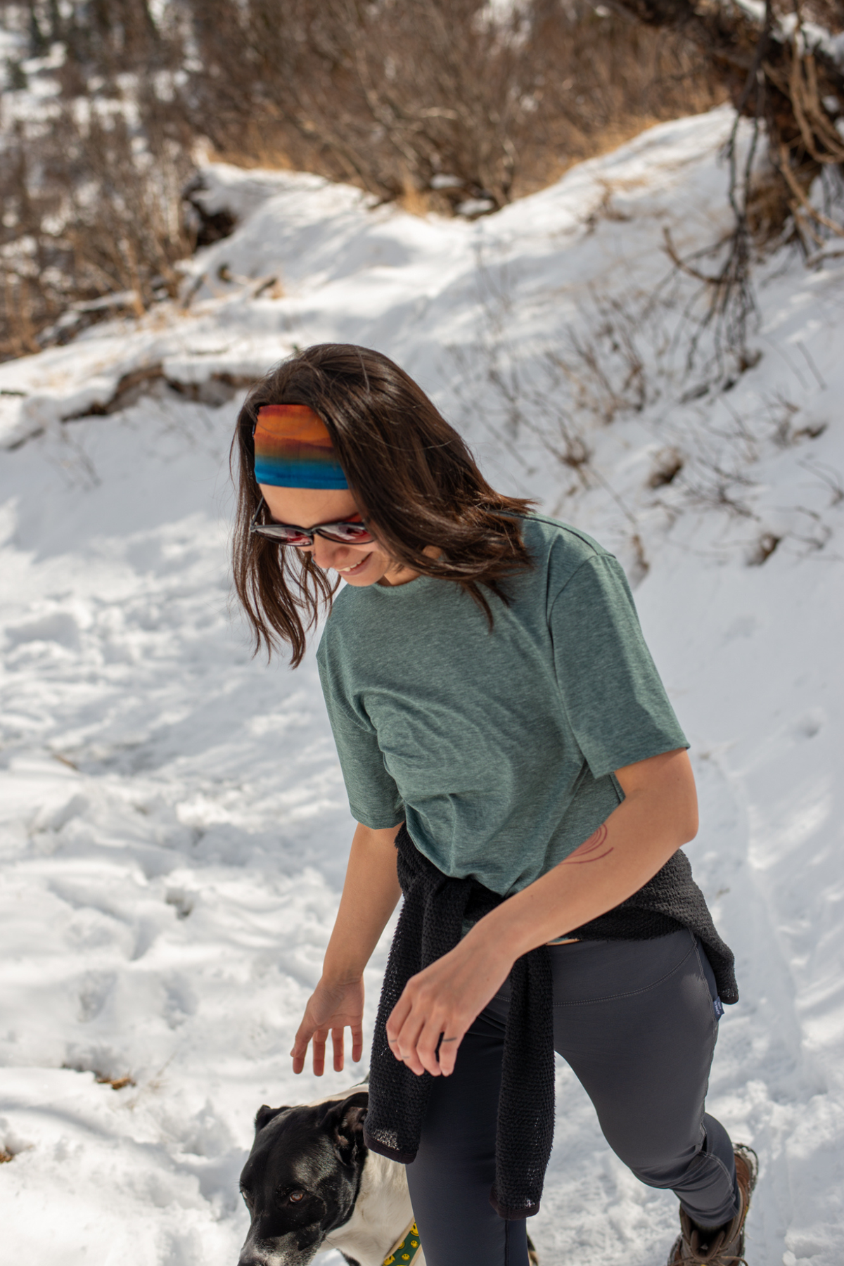 Alpine fit Merino wool lined headband grasslands on woman, full view, snowy background with dog