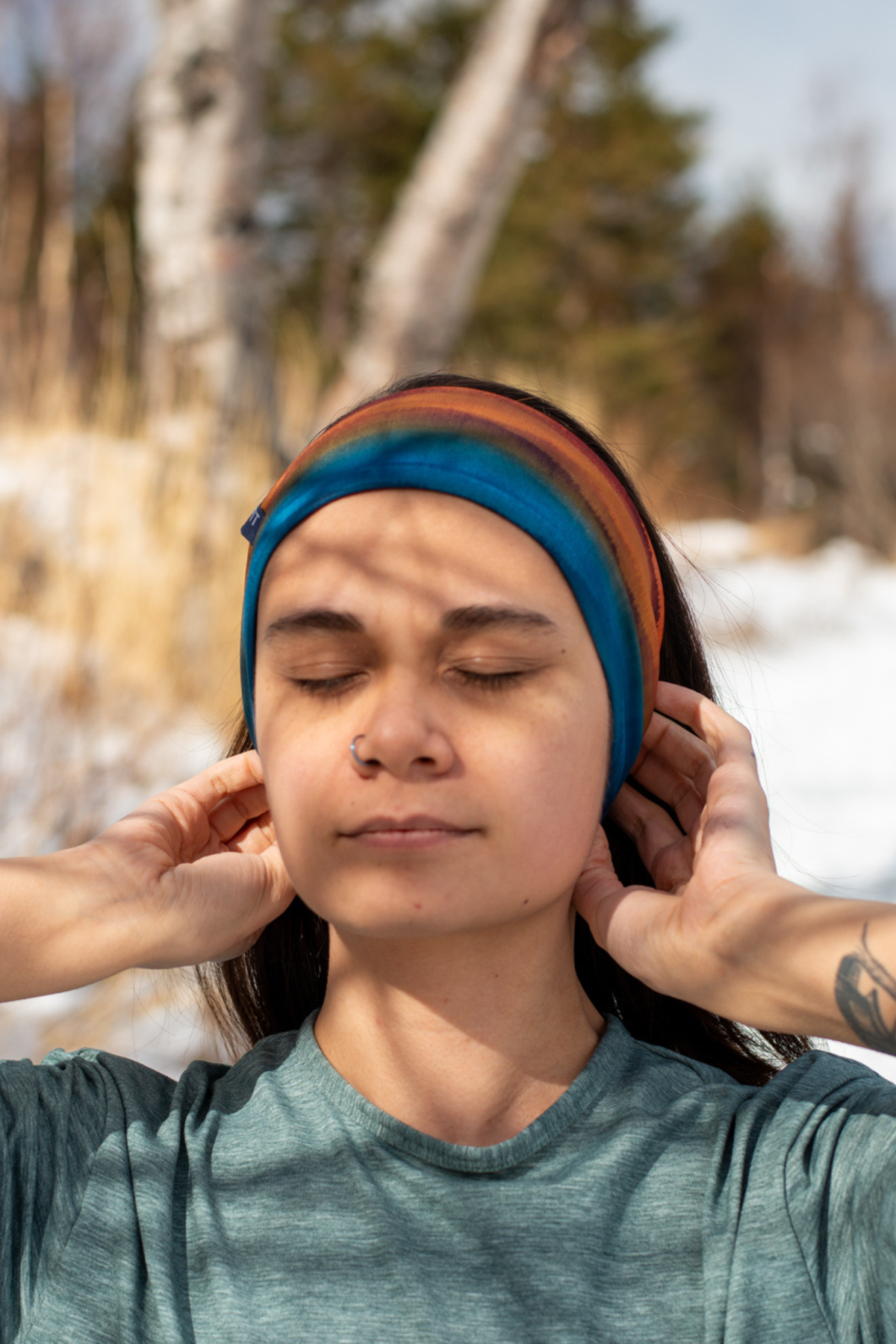 Alpine Fit Trailhead Cozy Fleece Headband Grasslands, Person wearing a colorful headband in a snowy forest setting