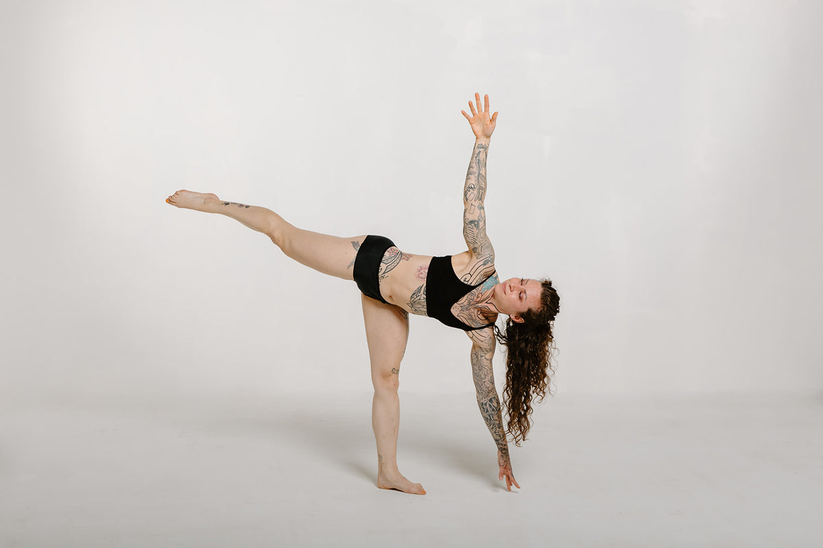 Alpine Fit Athletic Hipster Black on a woman, full view while stretching, off-white background