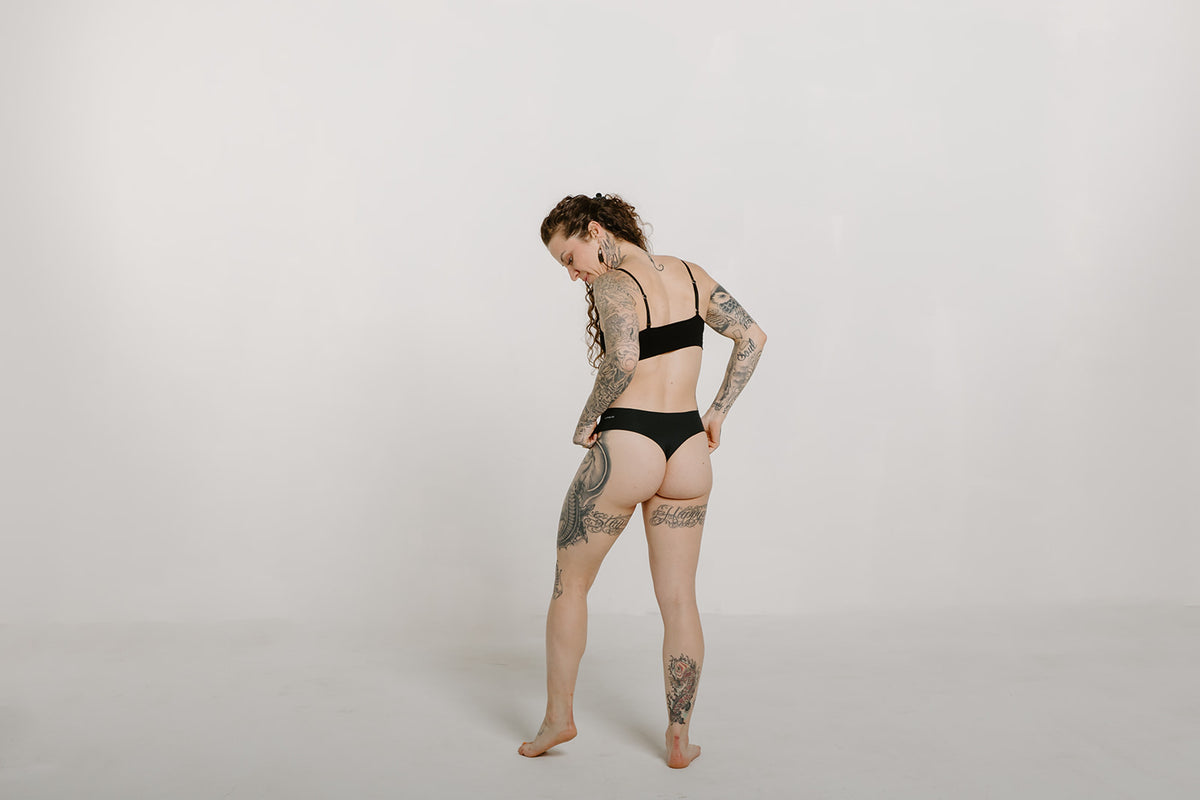 Alpine Fit Athletic Thong Obsidian Cove Black, Woman wearing athletic thong full back view with off white background