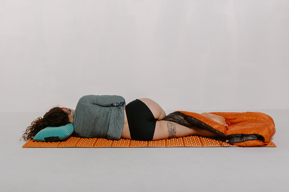 Alpine Fit Athletic Hipster Black on a woman, full right side view, lying down, off-white background