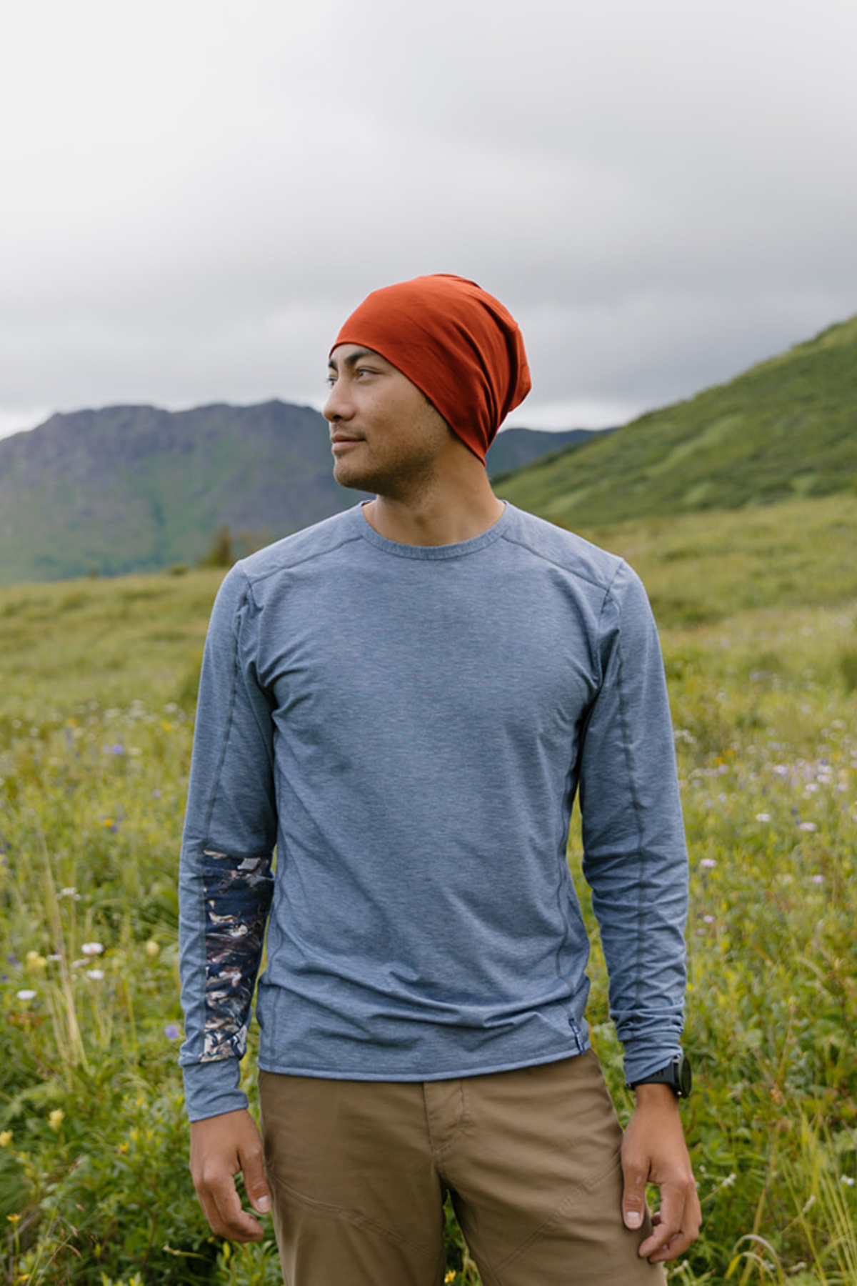 Alpine Fit Men's Treeline Long Sleeve Misty Bering Sea Blue, Man wearing a blue long sleeve top and red beanie in a grassy field
