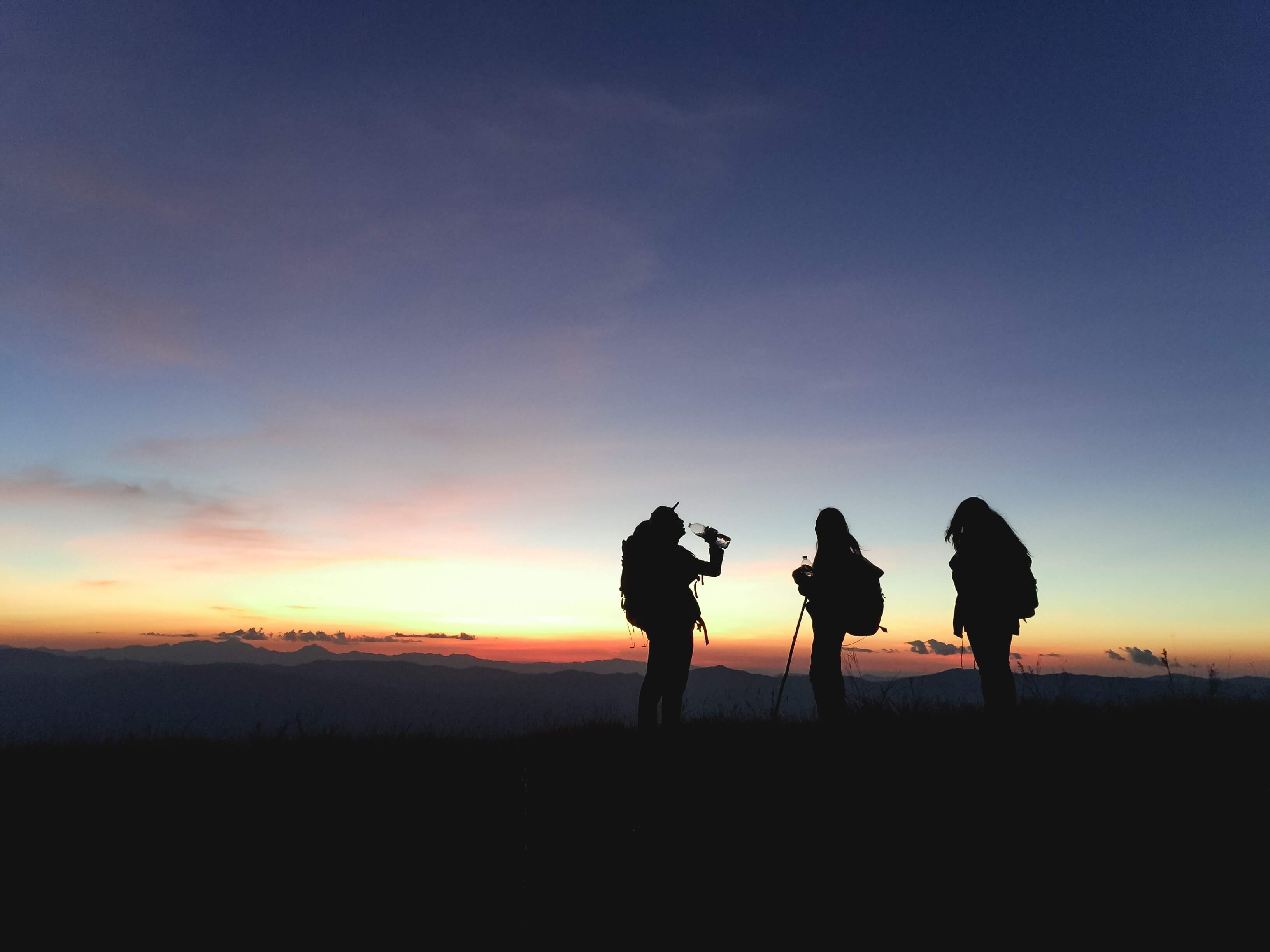 Silhouette of three people on hike